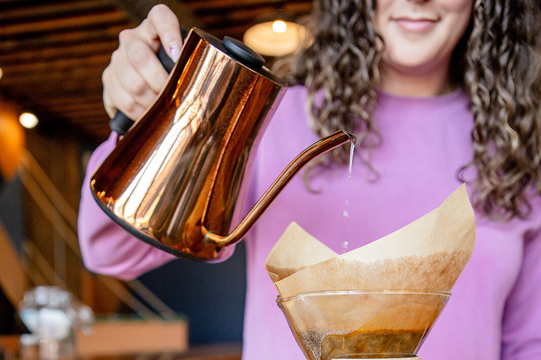 A barista using the pour over method for coffee at the counter