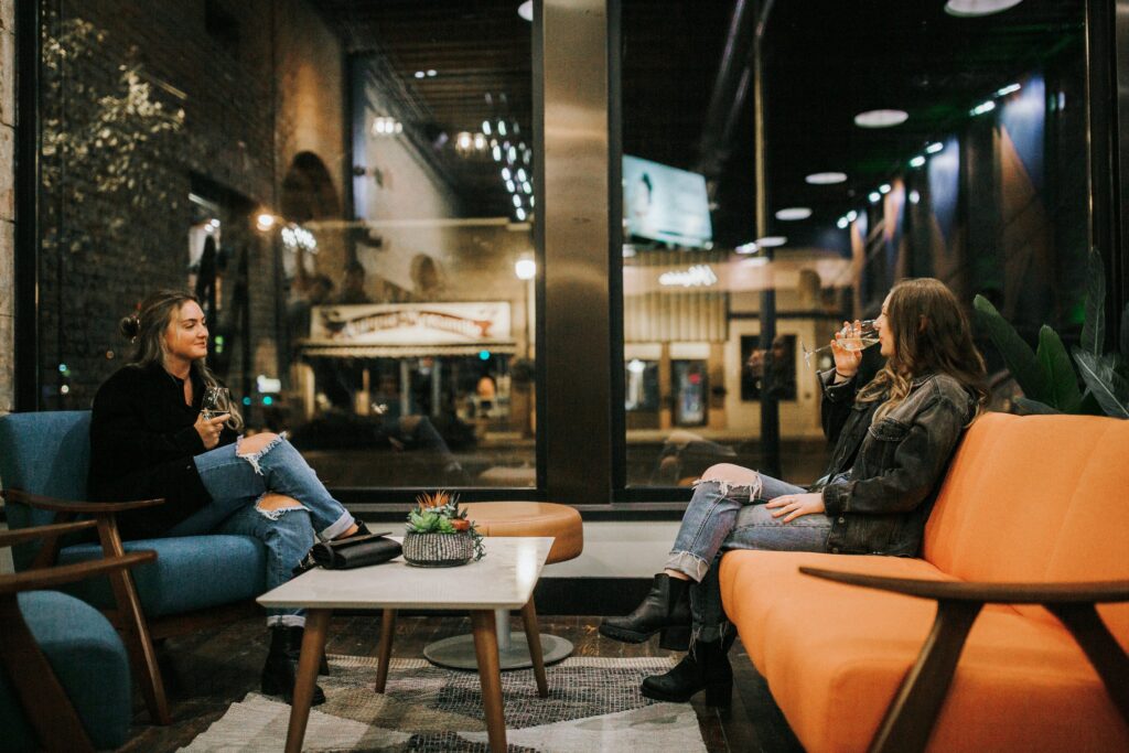 Two young women sitting across from each other drinking wine.