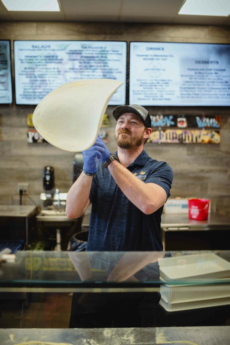 Male employee tosses dough in the air to make pizza at Danger von Dempsey's in Brookings