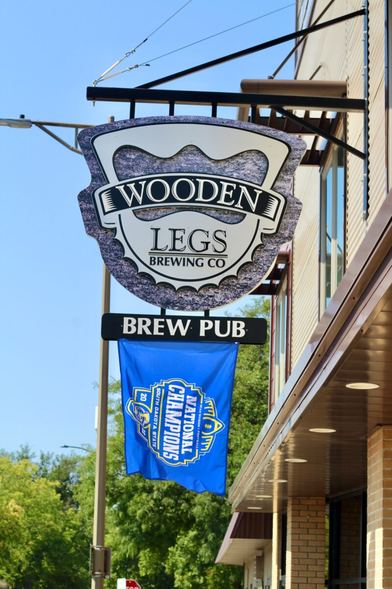 Wooden Legs Brewing Company's sign with a SDSU flag underneath