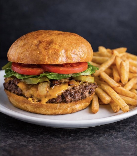 A burger on a toasted bun served with fries