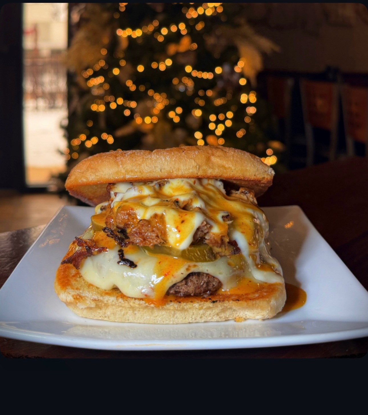 A burger with lots of cheese and sauce served on a ciabatta bun