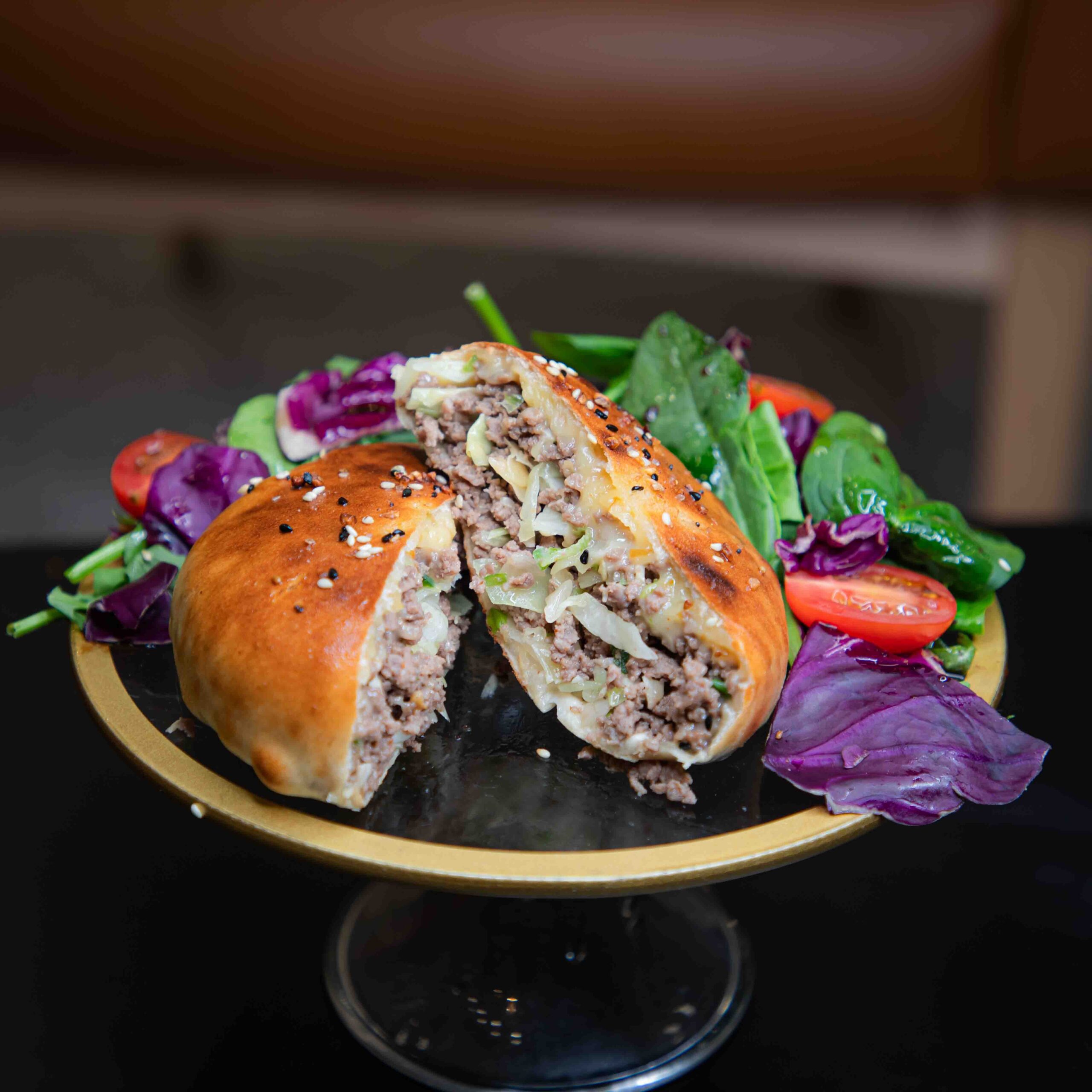 German-inspired hand burger in golden baked dough served with a winter greens salad