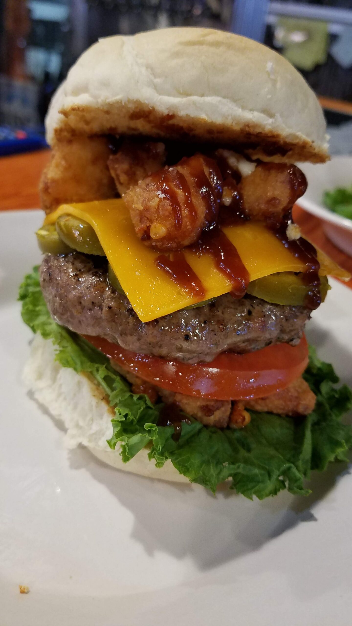 A burger topped with cheese curdys and jalapeños