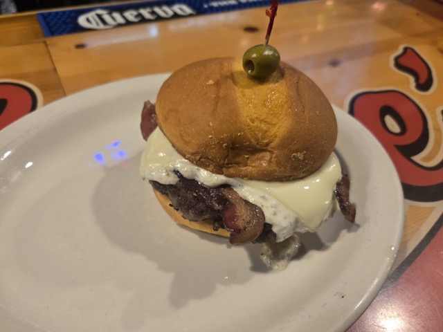 Burger with lots of cheese topped with a single olive